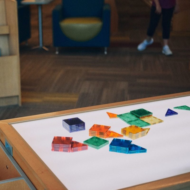 Magna-Tiles sit on a white play table at the library.