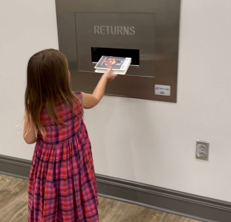 A girl returns an audio book at the automatic return at the South Huntsville Library.