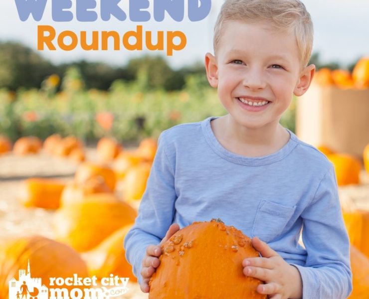 A boy in a blue shirt holds a warty orange pumpkin in front of a pumpkin patch.