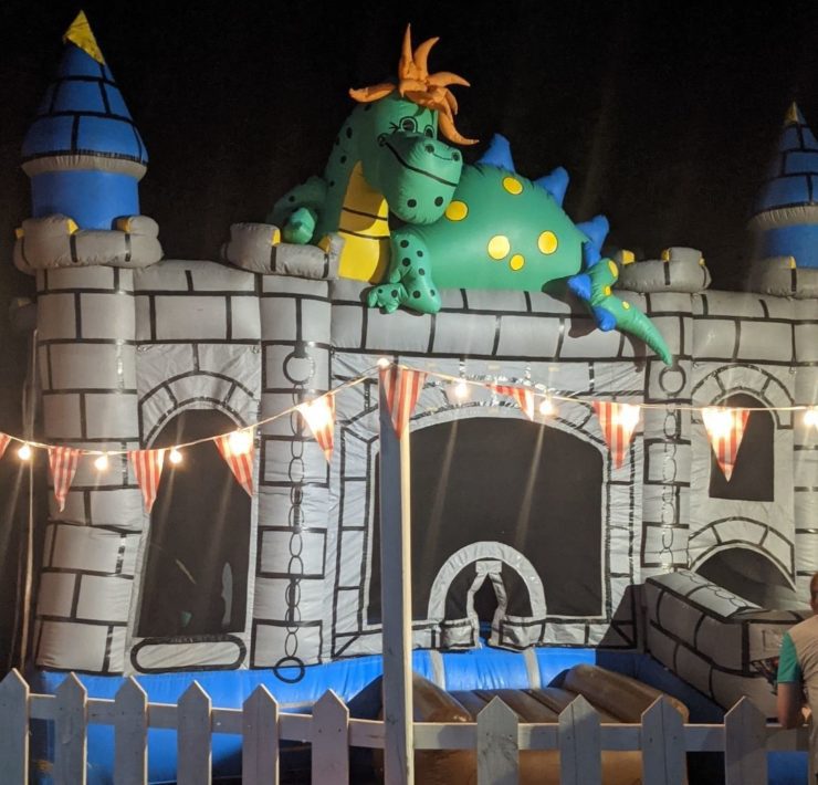 A green dragon sits atop a gray bouncy castle at Frankenville.