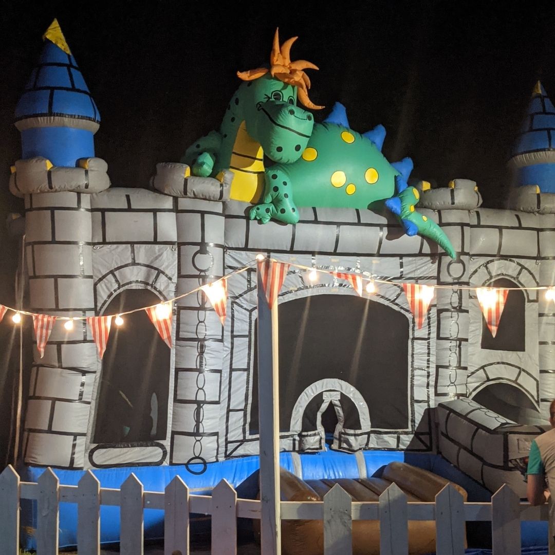 A green dragon sits atop a gray bouncy castle at Frankenville.