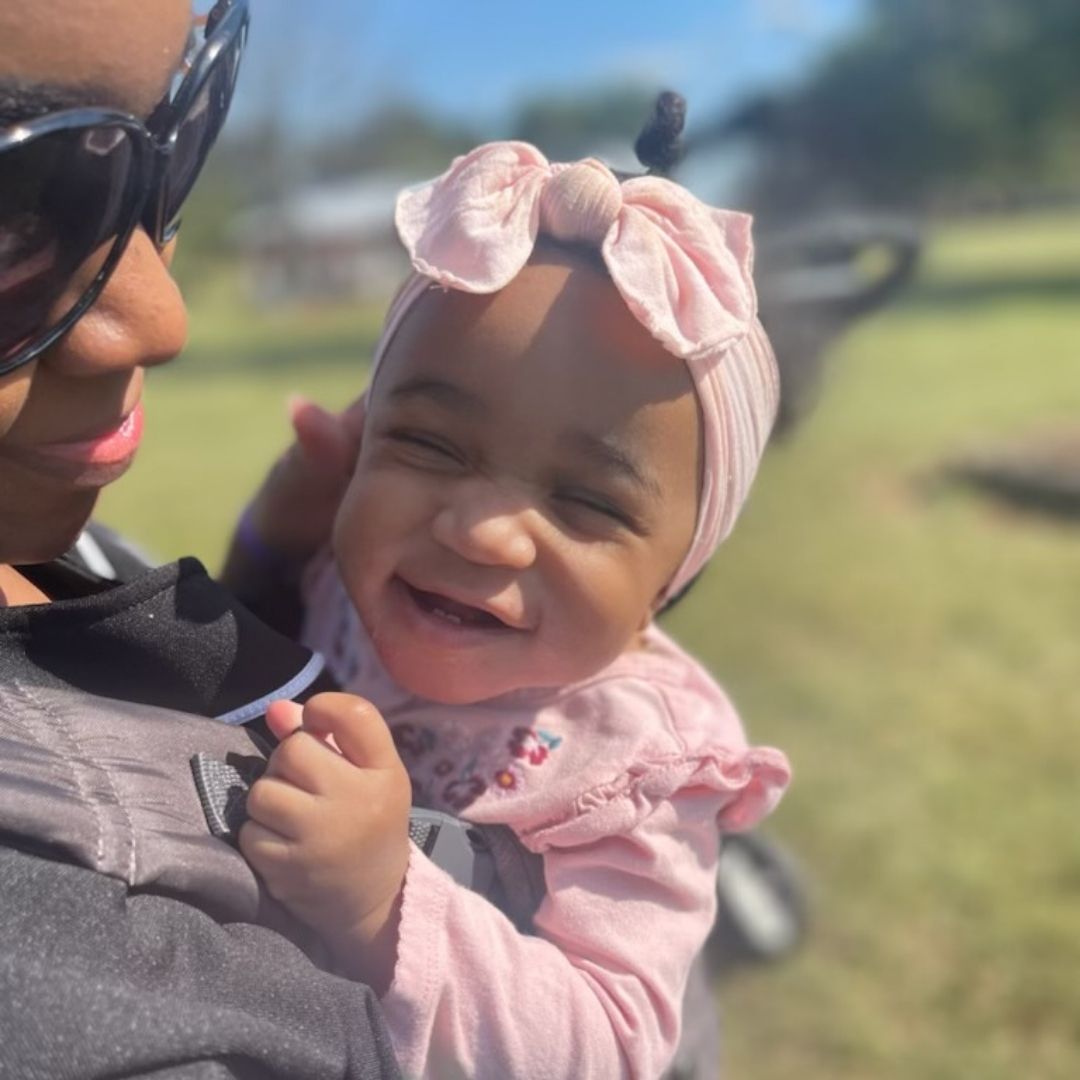 A young baby with a pink bow enjoys her visit to Lyon Family Farm.