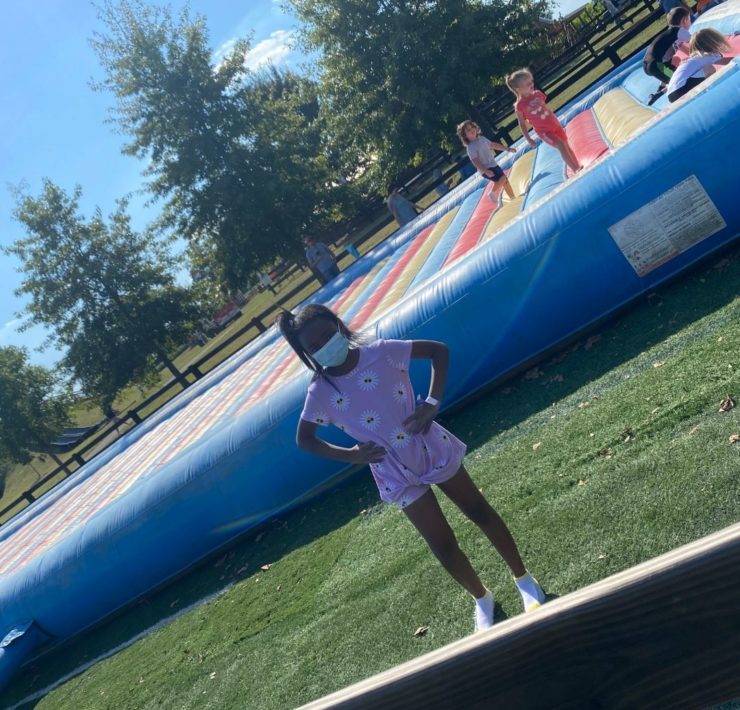 A young girl stands in front of the pillow bounce at Lyon Family Farm.