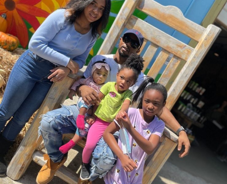 A family sits in a large wooden chair at Lyon Family Farm.