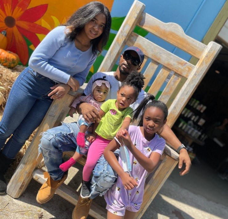 A family sits in a large wooden chair at Lyon Family Farm.