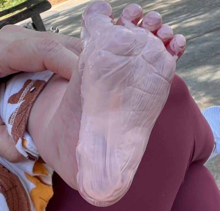 Beige paint covers a baby's foots as part of a craft.