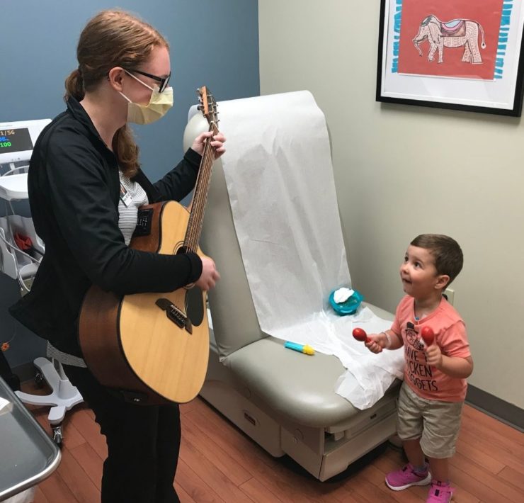 A young boy holds maracas and participates in the music therapy program during his visit to Huntsville Hospital.