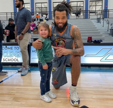 A young girl poses with a War Dawgs player after a game.