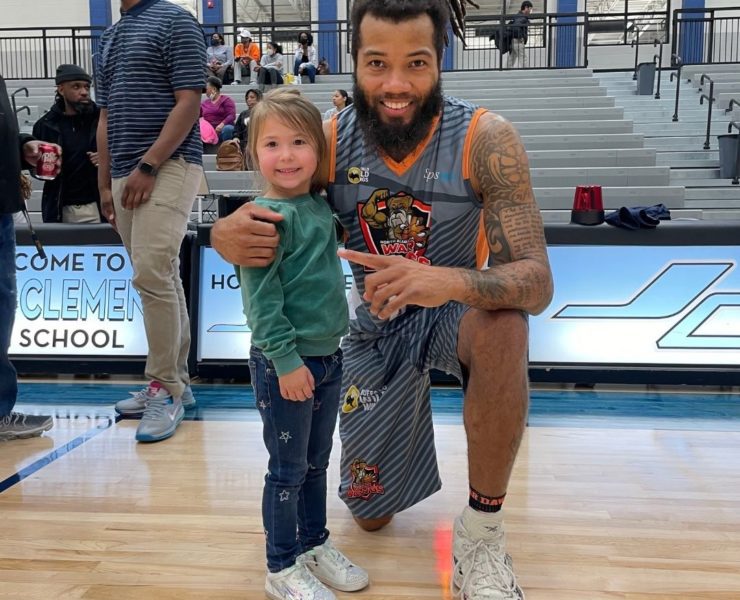 A young girl poses with a War Dawgs player after a game.