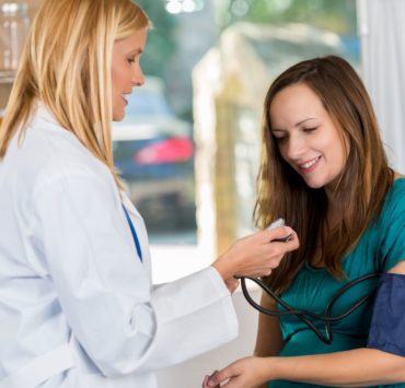 A pregnant woman in teal shirt visits with a North Alabama OBGYN.