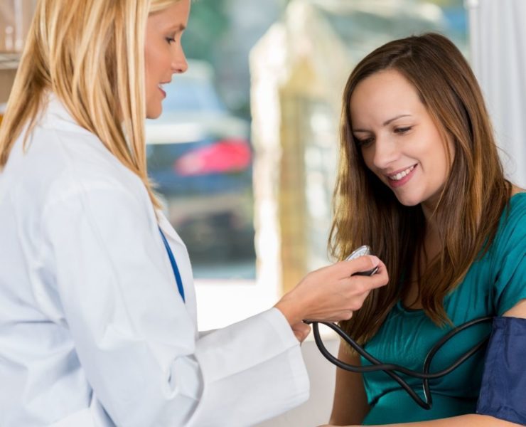 A pregnant woman in teal shirt visits with a North Alabama OBGYN.