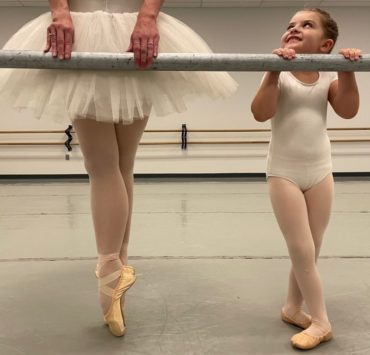young girl practicint ballet with older teen in a tutu