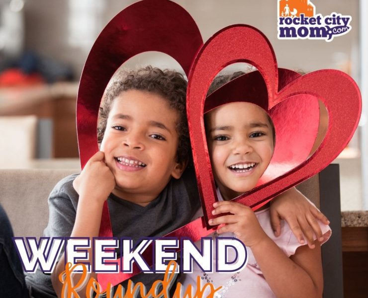 Two young children hold red paper hearts as part of their Valentine's Day fun during their Huntsville Weekend.