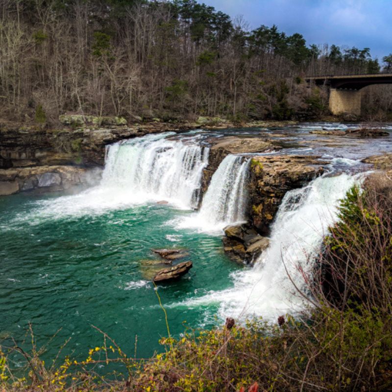 Three large waterfalls pour over into blue-green water at Little River Canyon.