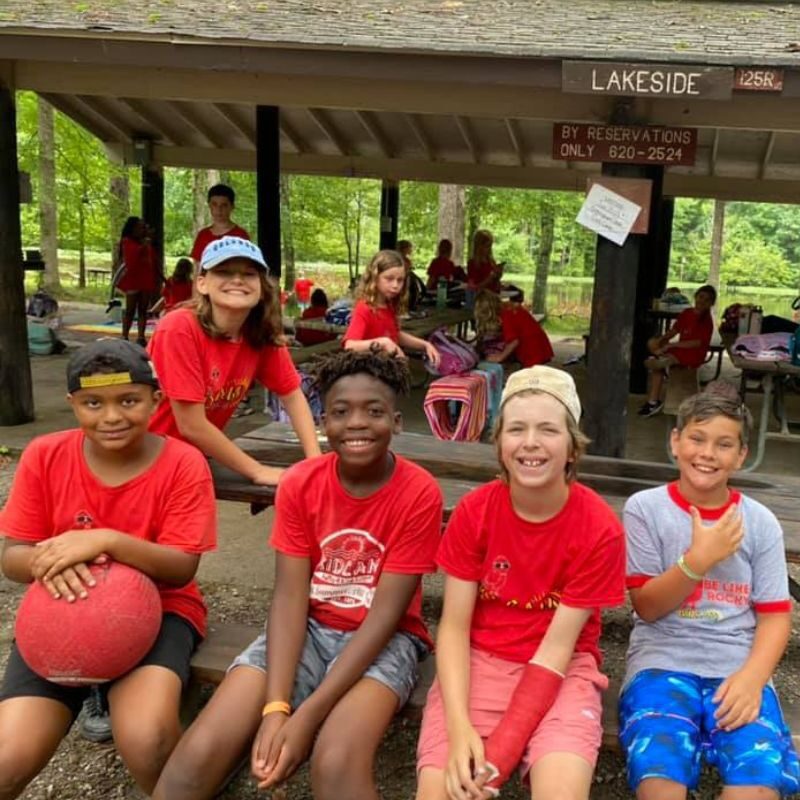 A group of tween boys sit together outside a pavilion area at KidCam Camps.