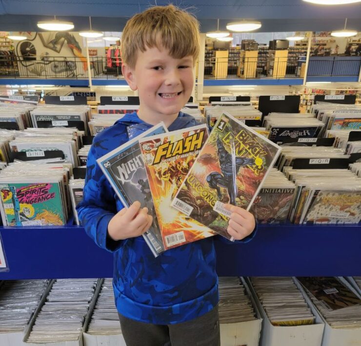 A young boy holds three comics that he found at McKay's Bookstore.