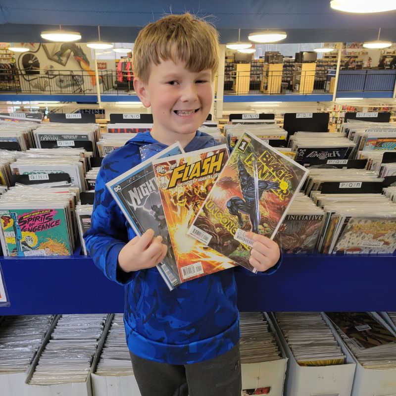 A young boy holds three comics that he found at McKay's Bookstore.