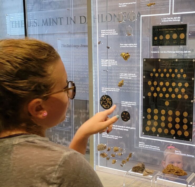 A preteen girl points toward a display of gold nuggets at the Dahlonega Gold Museum.