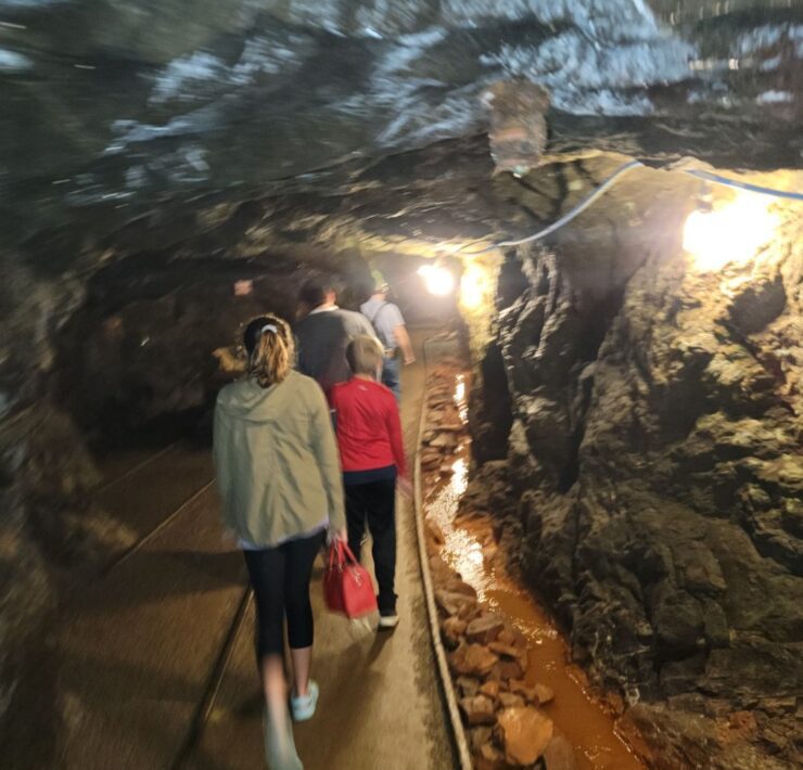A line of people follow rail tracks down into the depths of a mine.