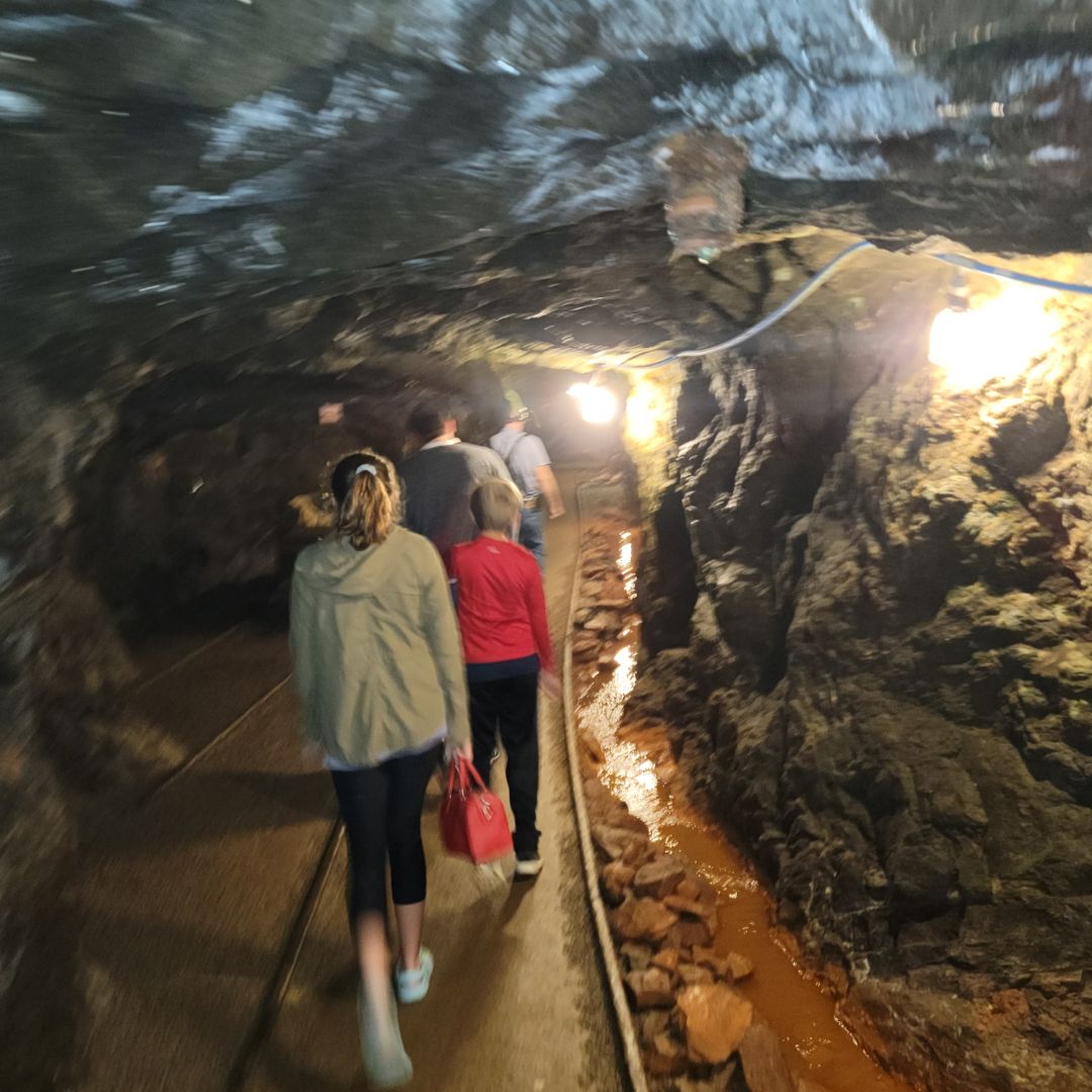 A line of people follow rail tracks down into the depths of a mine.
