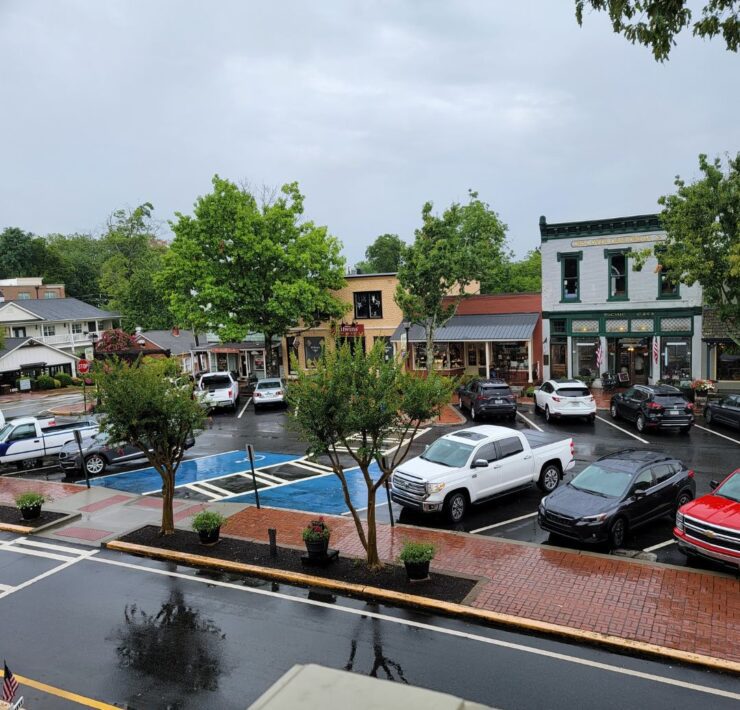 Downtown Dahlonega includes several connected shops of varying colors and heights, with several cars parked on the street.
