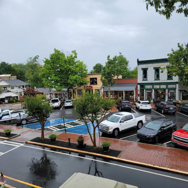 Downtown Dahlonega includes several connected shops of varying colors and heights, with several cars parked on the street.