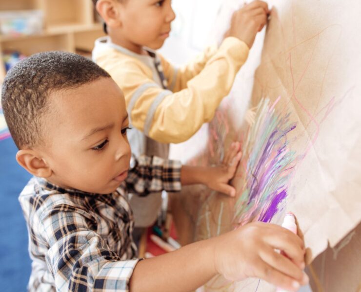 Two young children color on a piece of cardboard at a parents' night out.