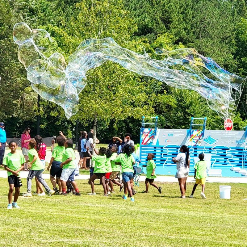 group of children running outside playing with bubbles